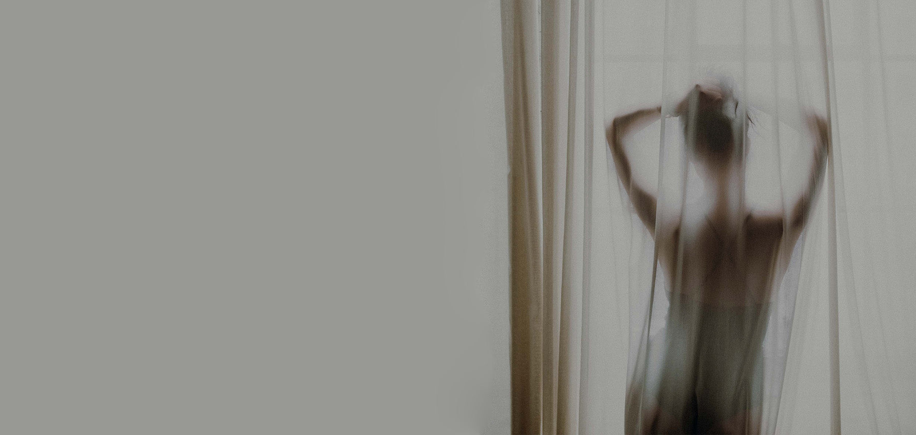 Minimal moody portrait, back view female silhouette behind sheer tulle curtain, neutral muted gray tone artistic boudoir lifestyle photography