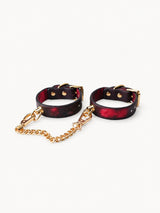 Submissive Collars, red black gradient leather wrist cuffs with gold chain, elegant pick for Date Night Gifts on white backdrop