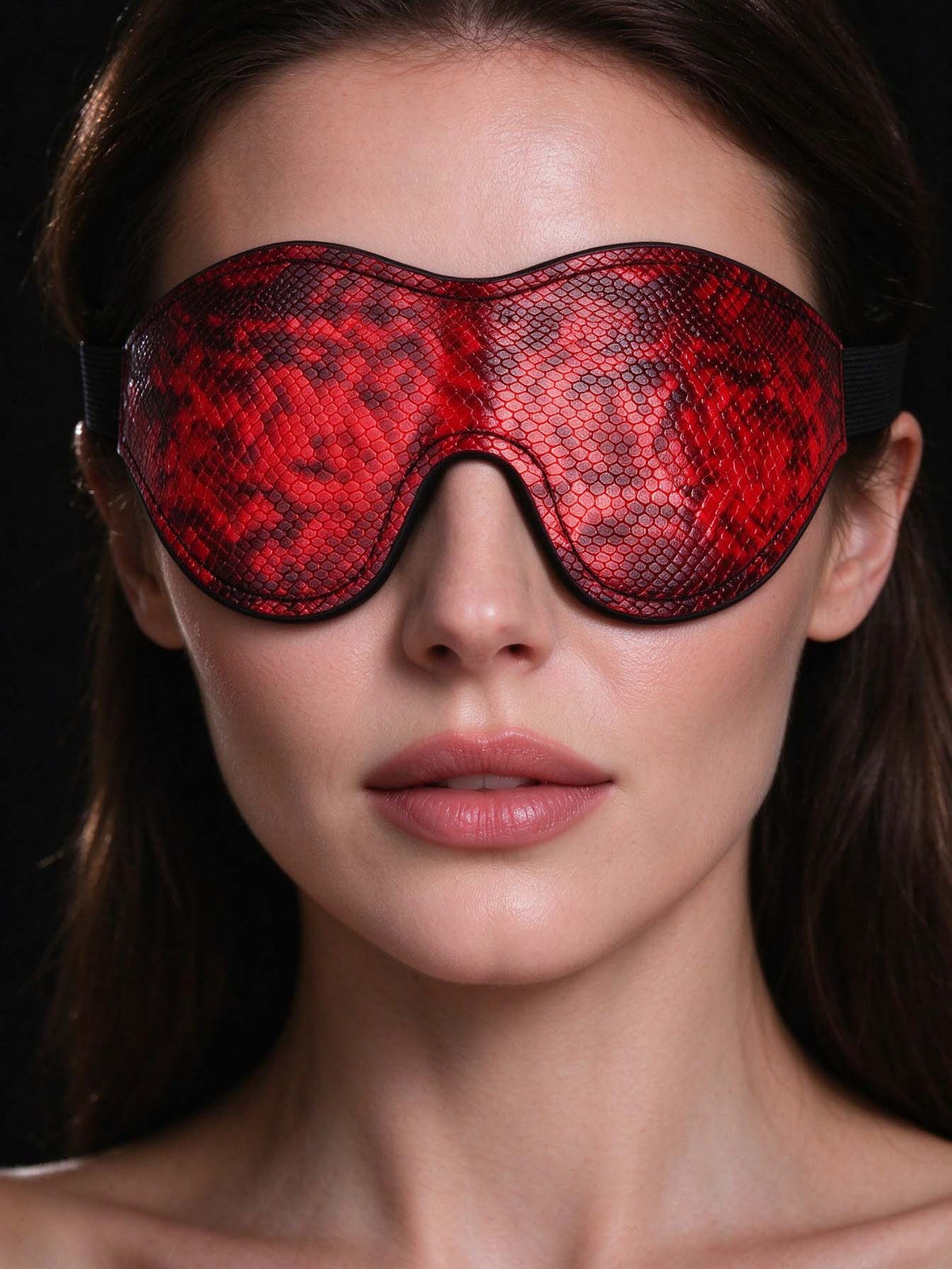close up portrait of woman wearing red snake print leather blindfold mask contoured faux leather eye covering dark background romantic date night ideas gifts for her