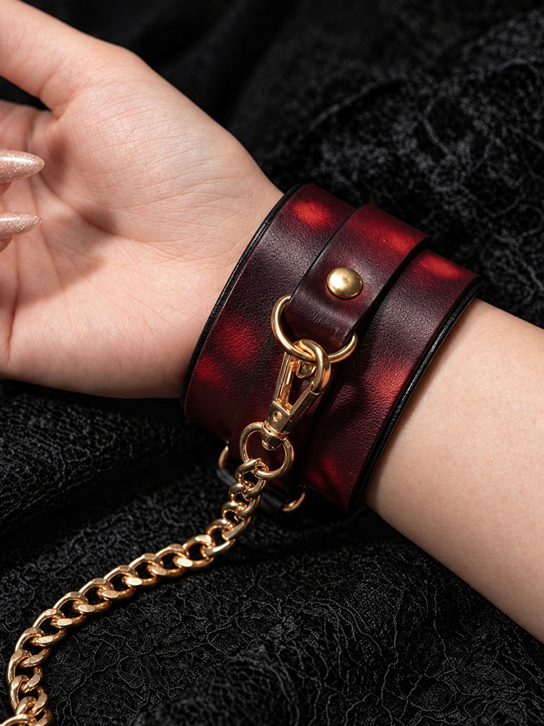 Closeup of Breathless thermochromic wrist cuff, red gradient temperature color changing faux leather with gold snap rivet and D ring hardware
