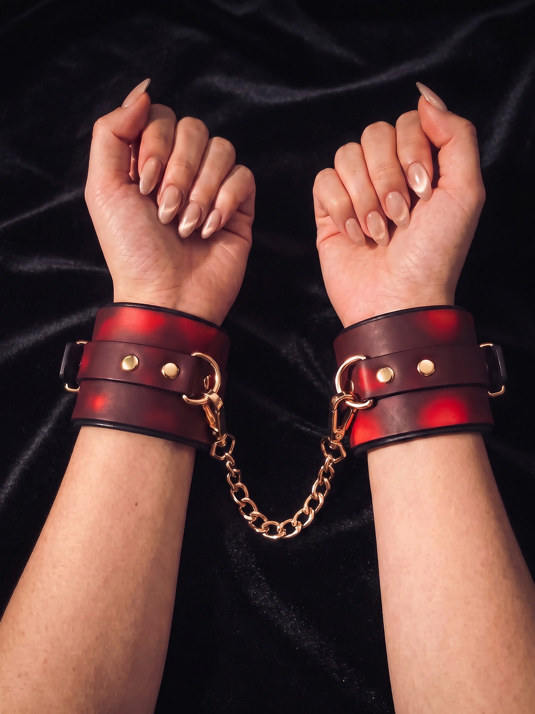 Front view of Breathless thermochromic wrist cuffs set, red gradient temperature changing leather restraints with gold hardware worn on both wrists