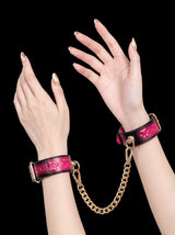 handchain thermochromic leather wrist cuffs with embossed heart paw print pattern heat reactive pink marks polished gold metal hardware worn on both hands solid black background