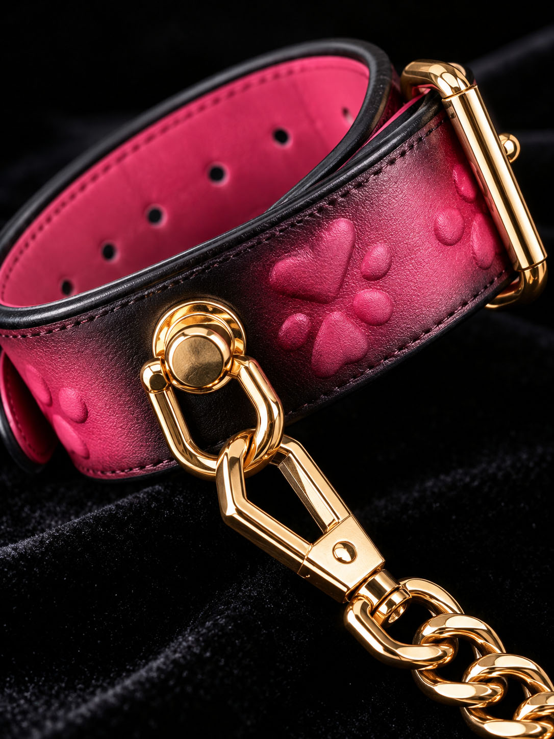 handchain thermochromic leather wrist cuffs close up embossed heart paw print pattern heat reactive pink marks polished gold metal buckle and chain on black velvet fabric