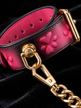 handchain thermochromic leather wrist cuffs close up embossed heart paw print pattern heat reactive pink marks polished gold metal buckle and chain on black velvet fabric