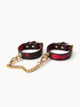 handchain thermochromic leather wrist cuffs with paw print pattern heat reactive red marks polished gold metal hardware and linked chain on plain white background