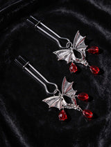 side angle close up of silver bat wing jewelry for nipple red crystal pendants lying on black velvet fabric dark gothic jewelry couples gifts