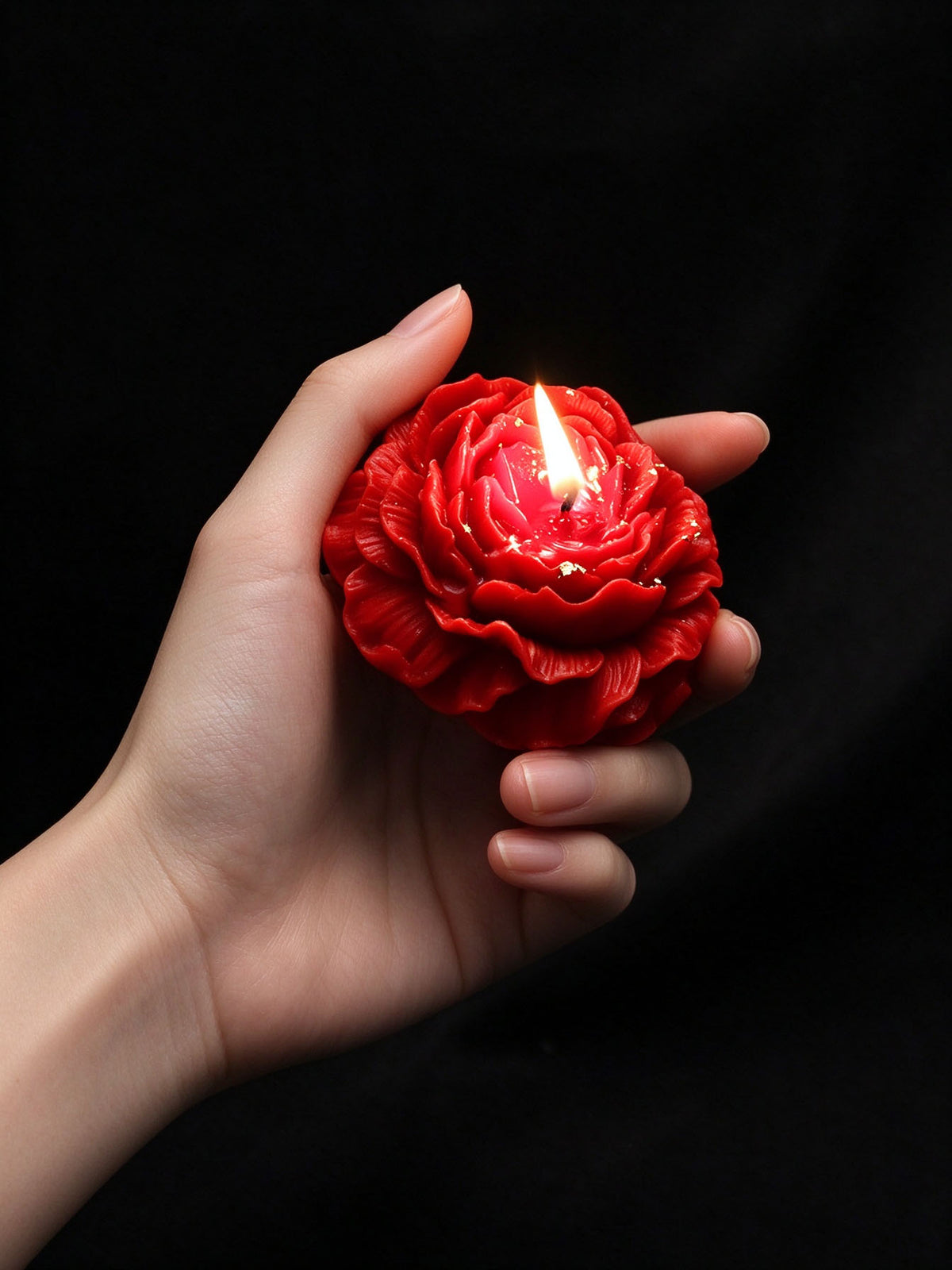 Low Temp Wax Play Candles, vivid red rose candle held in one hand, warm soft lighting on petal details