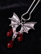 close up of gothic bat charm for nipple clamps antique silver bat pendant with teardrop red crystal beads dark velvet surface goth fashion decorative jewelry