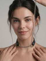 Woman posing with the Pulling Fashion and Fun Choker, chain trailing upward in a fashion-forward look