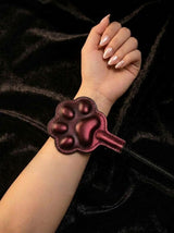 Thermochromic leather paw paddle worn on wrist, dark red gradient temperature color changing paw shaped pad with wrist strap, black velvet background