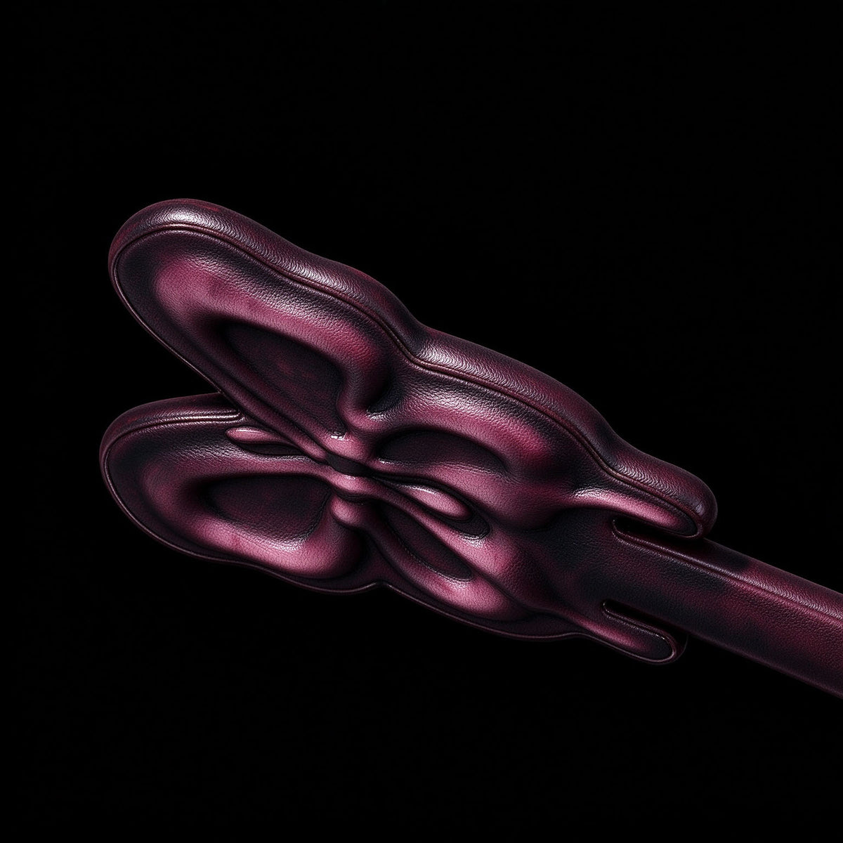 close up of thermochromic leather butterfly paddle 3d embossed butterfly texture deep plum leather on solid black background