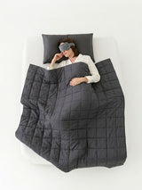 Full bed top-view of a weighted blanket for adults draped over a sleeping woman