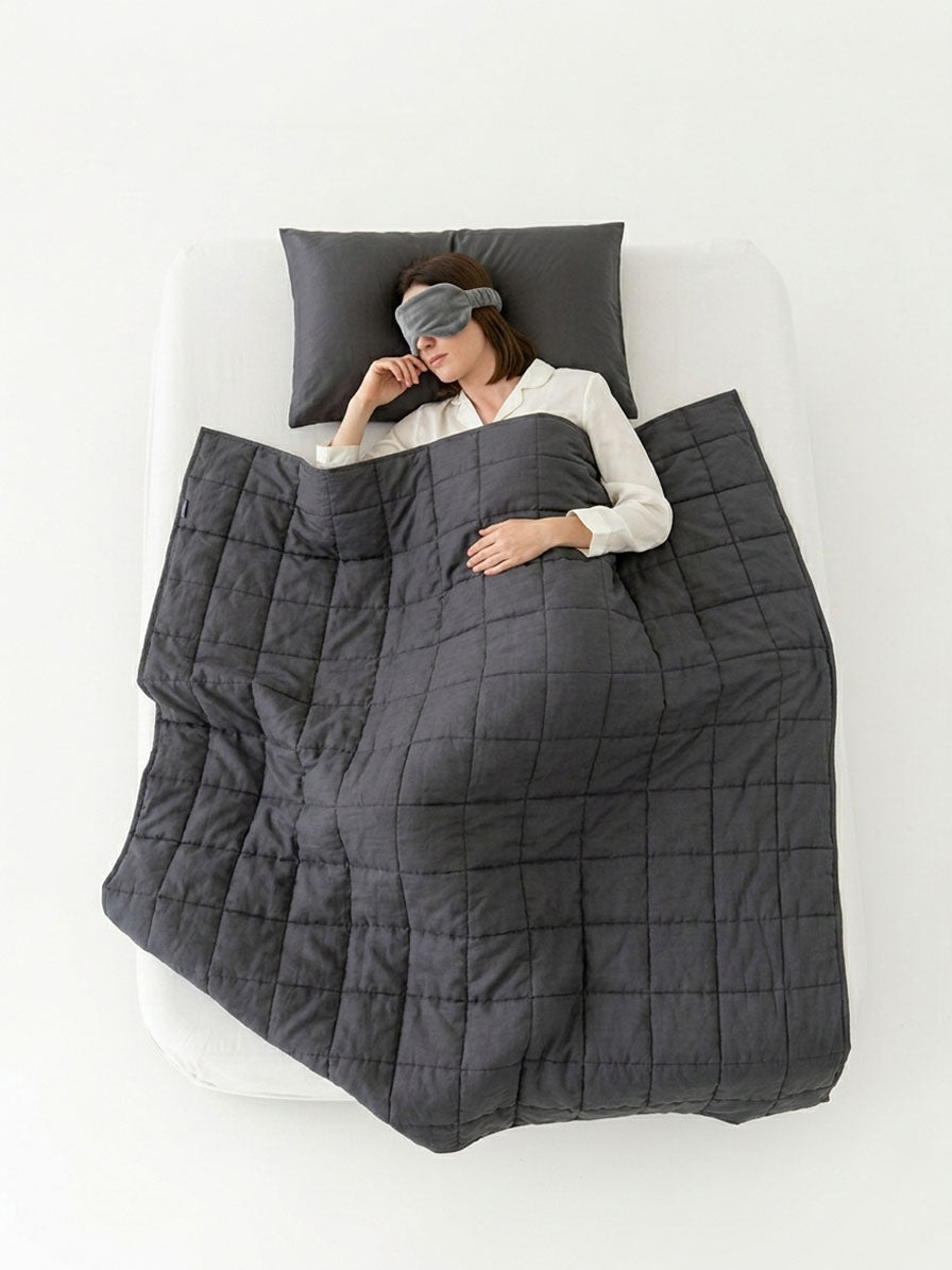 Full bed top-view of a weighted blanket for adults draped over a sleeping woman