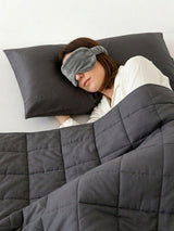 Woman sleeping under a Duska weighted blanket for adults, resting on a branded pillowcase