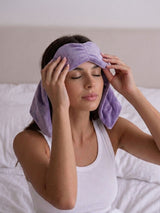 Woman gently placing a weighted eye mask on her face, used for relaxation and the everyday benefits of a weighted eye mask